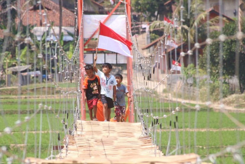 Anak warga Sumedang Selatan membawa bendera Merah Putih di Jembatan Harapan.