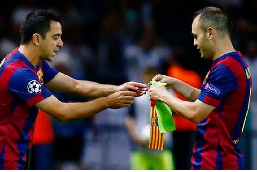 Andres Iniesta (kanan) memberikan ban kapten kepada Xavi