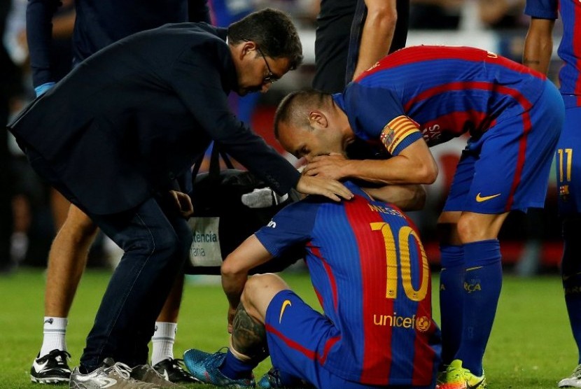 Andres Iniesta (kanan) menghibur Lionel Messi yang cedera.