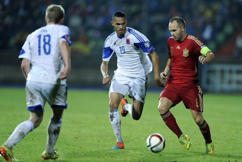 Andres Iniesta of Spain (R) fights for the ball with Dwayn Holter of Luxembourg (C) during their Euro 2016 qualification soccer match at the Josy Barthel stadium in Luxembourg October 12, 2014.