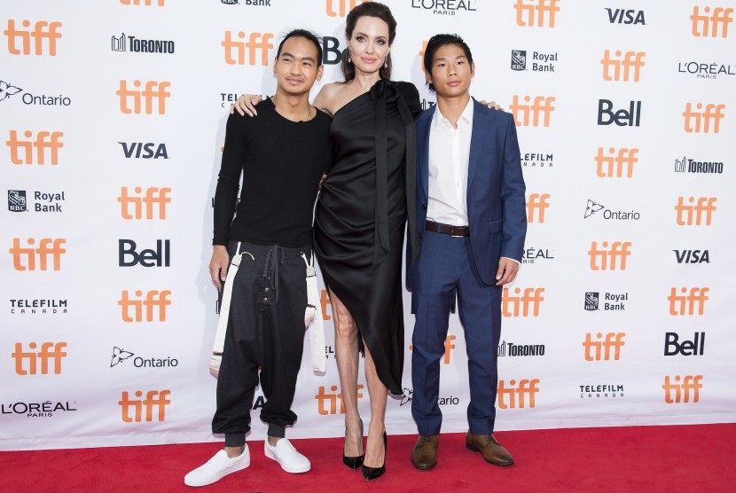 Angelina Jolie (tengah) diapit putranya Maddox (kiri) dan Pax (kanan). 