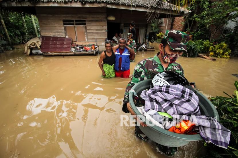 Anggota Babinsa TNI Kodim 0103 Aceh Utara membantu evakuasi korban banjir di Desa Hasan Kareung, Blang Mangat, Lhokseumawe, Aceh, Sabtu (5/12/2020). Data Badan Penanggulangan Bencana Daerah (BPBD) menyebutkan bencana banjir terus meluas, merendam 502 desa di 20 kecamatan di Aceh Utara, menyebabkan sekitar seribu warga mengungsi. 