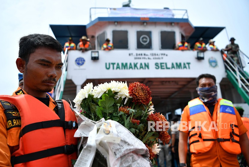 Anggota Basarnas memegang bunga saat berlangsung prosesi tabur bunga bagi korban tenggelamnya KM Sinar Bangun di kawasan titik tenggelamnya kapal di Danau Toba, Sumatera Utara, Senin (2/7). 