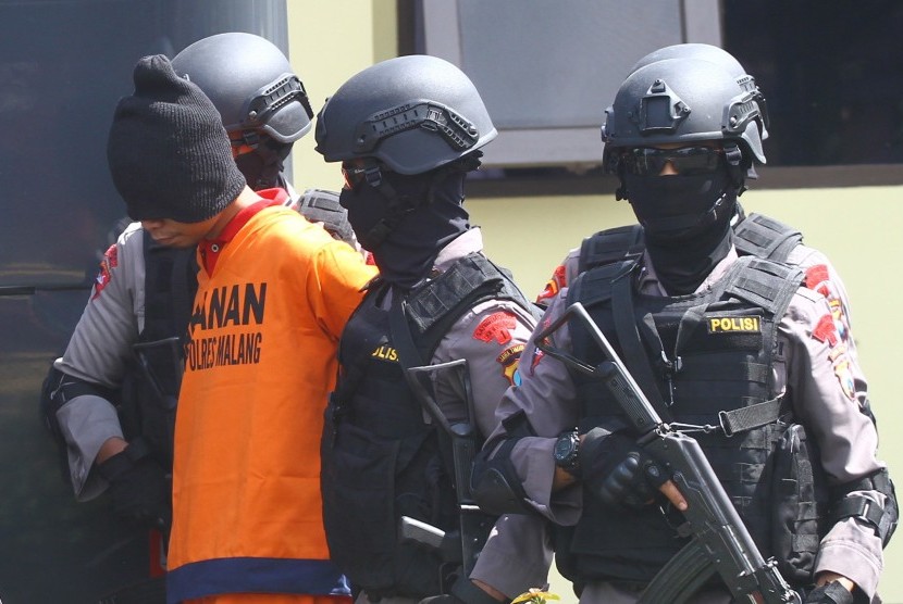Anggota Brimob bersenjata lengkap menggiring salah satu dari dua tersangka teroris menuju mobil saat dipindahkan di Markas Detasemen B Brimob Ampeldento, Malang, Jawa Timur, Rabu (3/2).