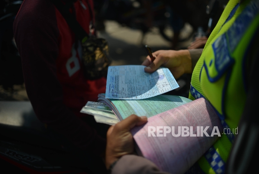 Anggota dari Polres Metro Jakarta Selatan memberikan surat tilang kepada pengendara motor saat menggelar Operasi Patuh Jaya.