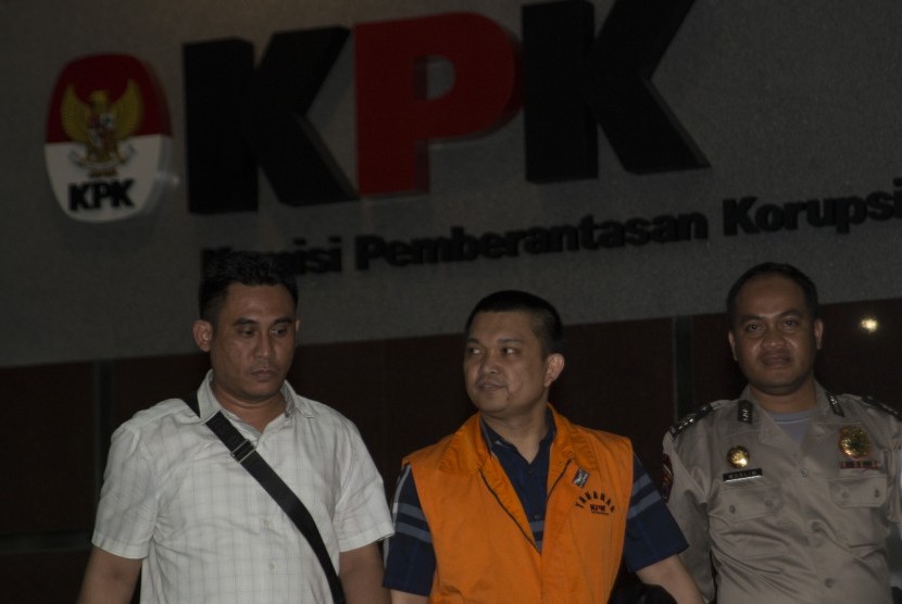 Anggota DPR Komisi XI dari Fraksi Partai Golkar Aditya Moha (tengah) berjalan keluar menggunakan rompi tahanan usai diperiksa di gedung KPK, Jakarta, Ahad (8/10) dini hari. 