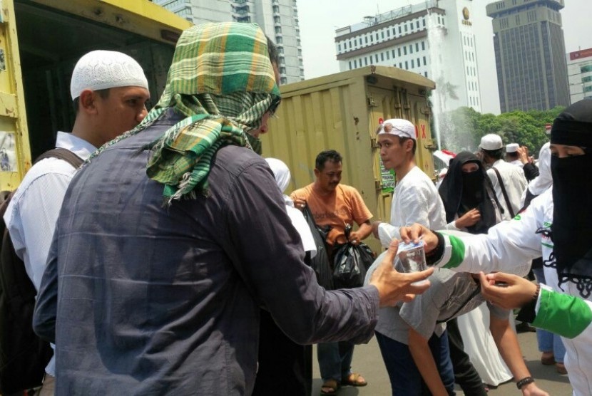 Anggota FPI, Yuni, membagikan nasi bungkus kepada pendemo usai shalat Jumat di Bundaran Patung Kuda, Jumat (4/11).