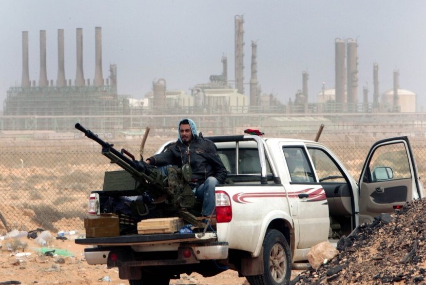 Anggota gerilyawan antipemerintah memegang senjata antiserangan udara di depan kilang minyak Ras Lanouf, di timur Libya.