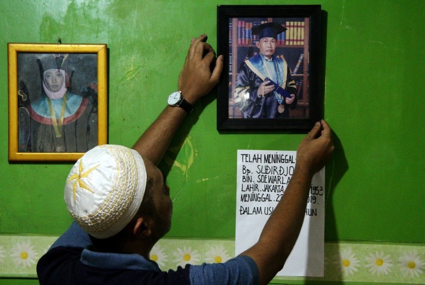 Anggota keluarga memperbaiki posisi foto Sudirdjo, seorang petugas Kelompok Penyelenggara Pemungutan Suara (KPPS) Pemilu serentak 2019 yang meninggal dunia usai mendapatkan perawatan di rumah sakit di Bekasi, Jawa Barat, Selasa (23/4/2019).