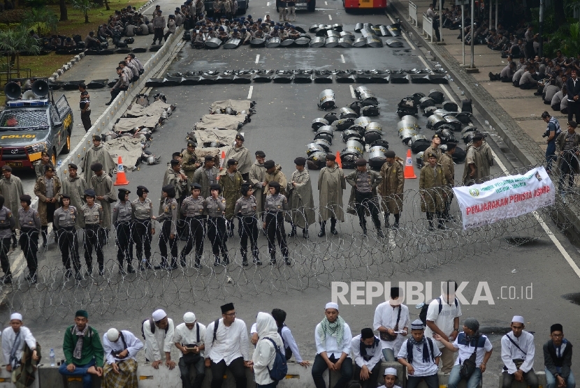 Anggota kepolisian berjaga saat ribuan massa melakukan aksi di bundaran Patung Kuda, Jakarta, Jumat (31/3). 