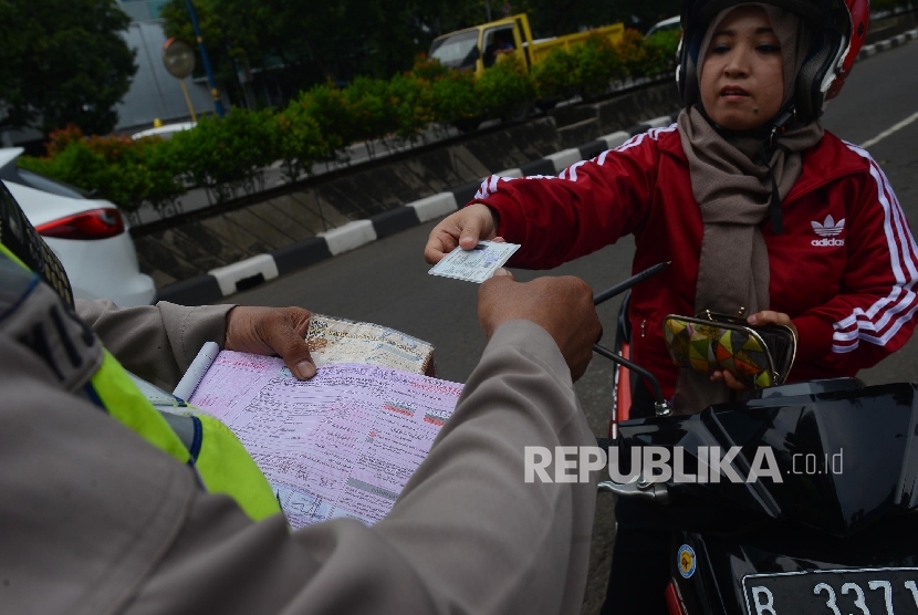  Anggota Kepolisian dari Polda Metro Jaya memeriksa kelengkapan surat berkendara pengemudi saat menggelar Operasi Simpatik Jaya di Jalan Rasuna Said, Jakarta Selatan, Ahad (20/3). (Republika/Raisan Al Farisi)