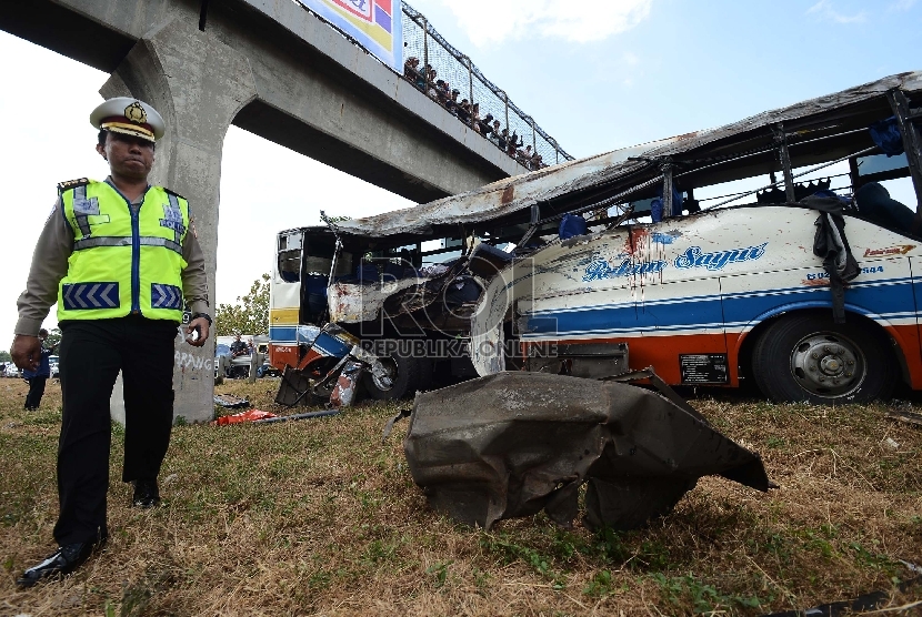 Anggota kepolisian melakukan identifikasi bus yang mengalami kecelakaan di Km 202 Tol Palikanci, Ciperna, Jawa Barat, Selasa (14/7).  (Republika/Raisan Al Farisi)