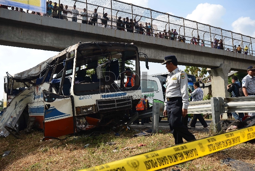 Anggota kepolisian melakukan identifikasi bus yang mengalami kecelakaan di Km 202 Tol Palikanci, Ciperna, Jawa Barat, Selasa (14/7).  (Republika/Raisan Al Farisi)