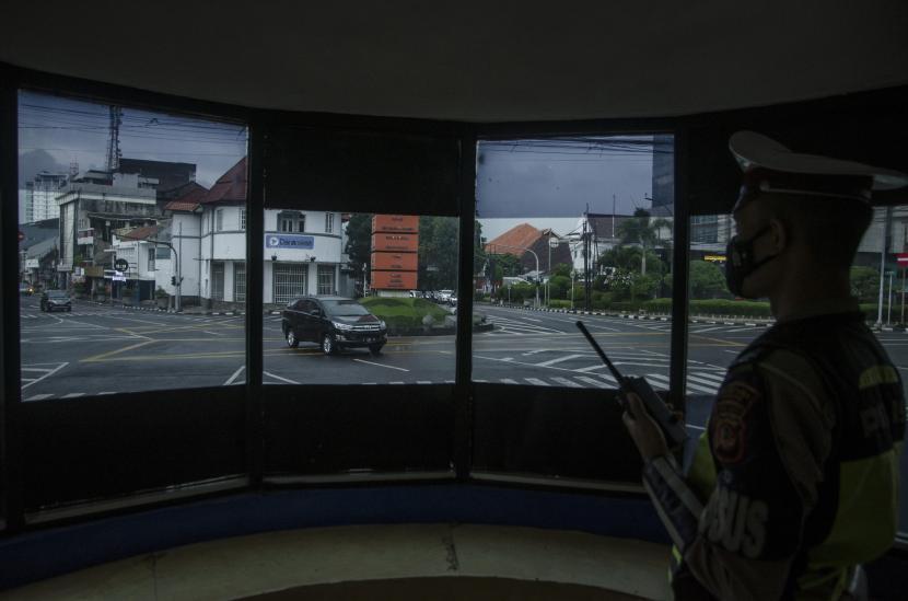 Anggota Kepolisian memantau arus lalu lintas di lokasi penerapan tilang elektronik Simpang Lima Kosambi, Bandung, Jawa Barat, Rabu (24/3/2021).