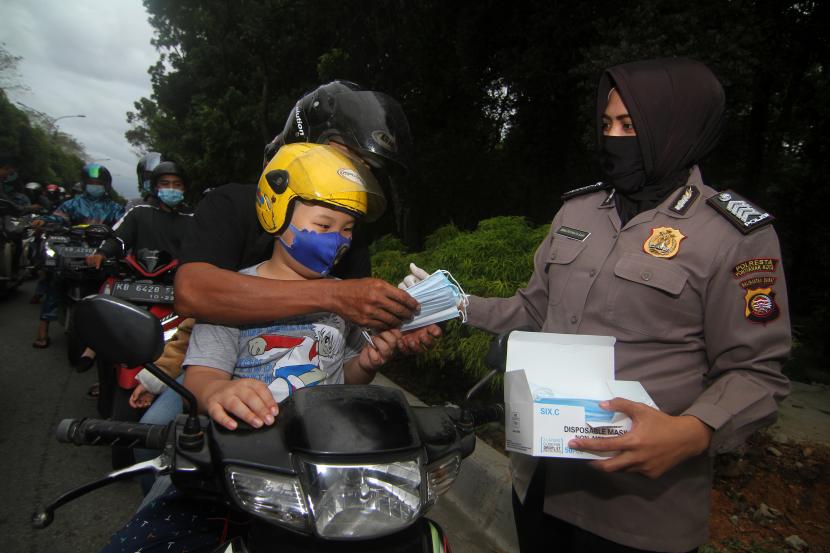 Anggota kepolisian membagikan masker (ilustrasi).