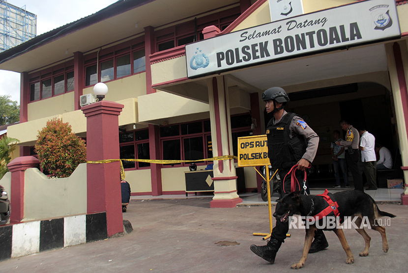 Anggota kepolisian membawa anjing pelacak memeriksa Tempat Kejadian Perkara (TKP) pasca kejadian pelemparan bom di halaman Polsek Bontoala, Makassar, Sulawesi Selatan, Senin (1/1).