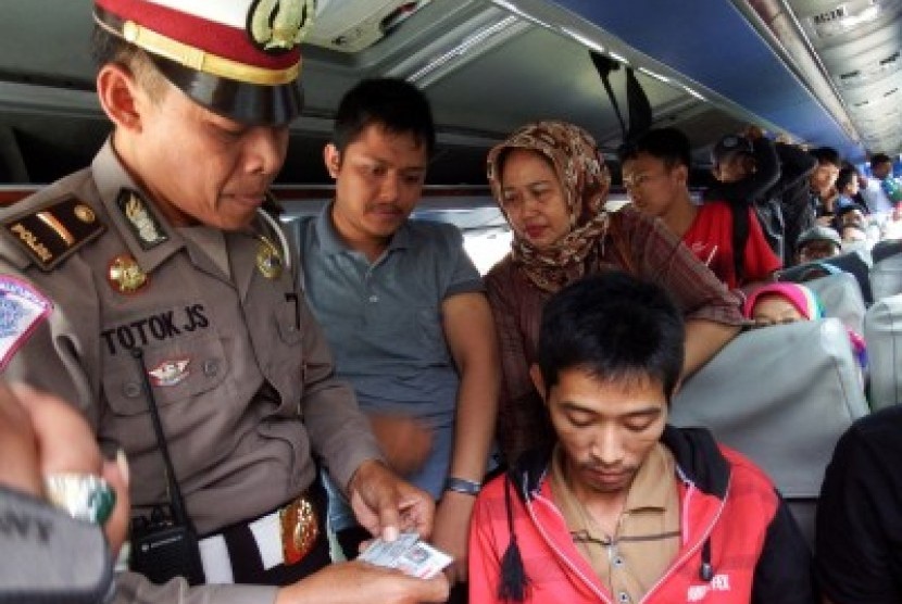 Anggota kepolisian memeriksa tanda pengenal dan barang bawaan penumpang bus di Jombang, Jawa Timur, Selasa (28/7). Menjelang pembukaan Muktamar ke-33 Nahdlatul Ulama (NU) di Jombang pada 1-5 Agustus 2015 pihak kepolisian setempat memperketat pengamanan gun