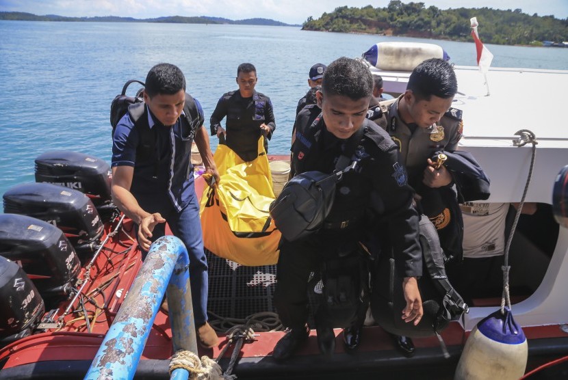 Anggota kepolisian Polda Kepri mengangkat kantong jenazah yang berisikan barang-barang yang diduga milik korban jatuhnya pesawat M28 Skytruck Pelabuhan Telaga Punggur, Batam, Kepulauan Riau, Minggu (4/12). 