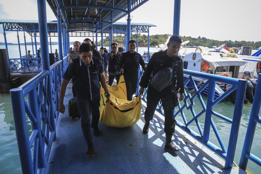 Anggota kepolisian Polda Kepri mengangkat kantong jenazah yang berisikan barang-barang yang diduga milik korban jatuhnya pesawat M28 Skytruck Pelabuhan Telaga Punggur, Batam, Kepulauan Riau, Minggu (4/12). 