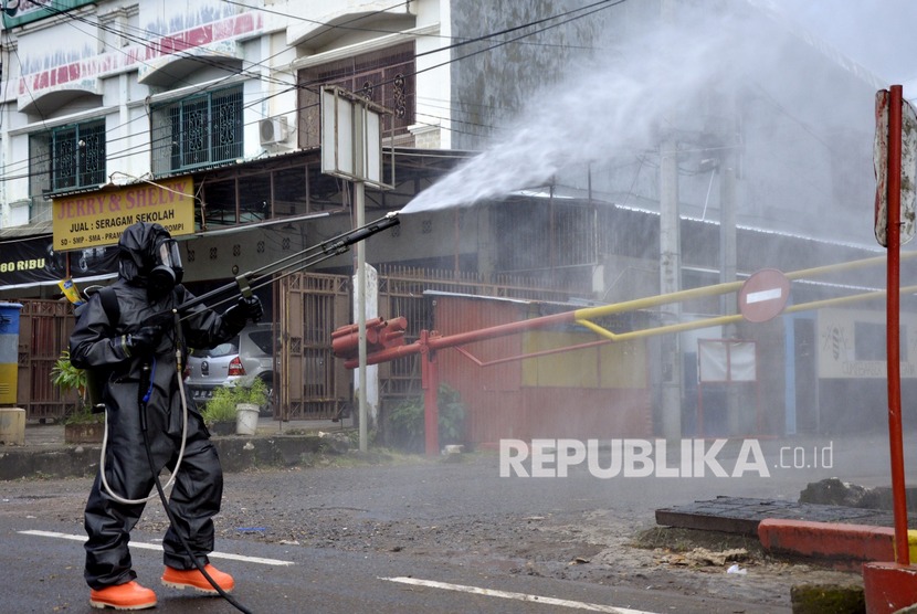 Anggota kepolisian Polda Sulsel menyemprotkan cairan di jalanan, Makassar, Sulawesi Selatan, Senin (16/3/2020).(Antara/Abriawan Abhe)