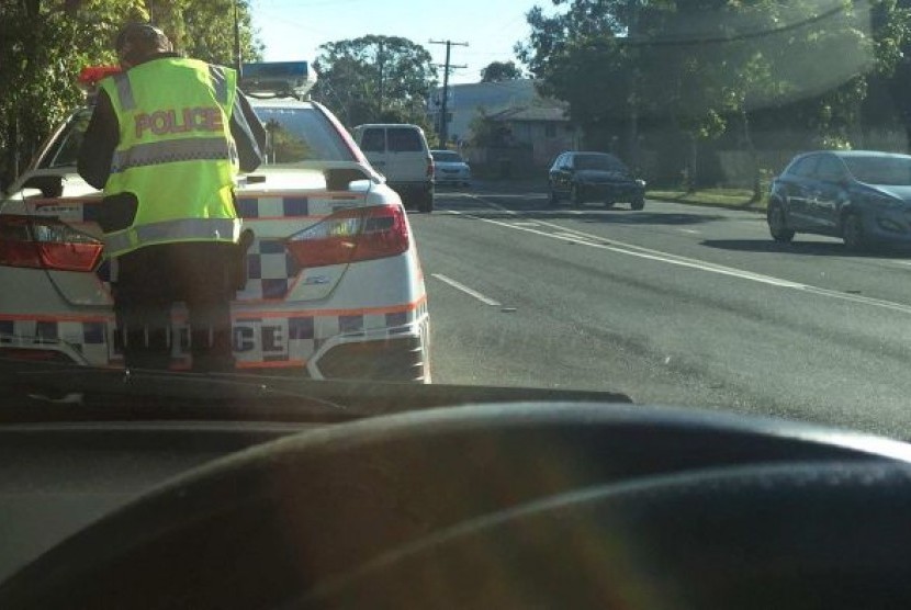 Anggota Kepolisian Queensland saat menemukan pelanggaran di jalan raya.