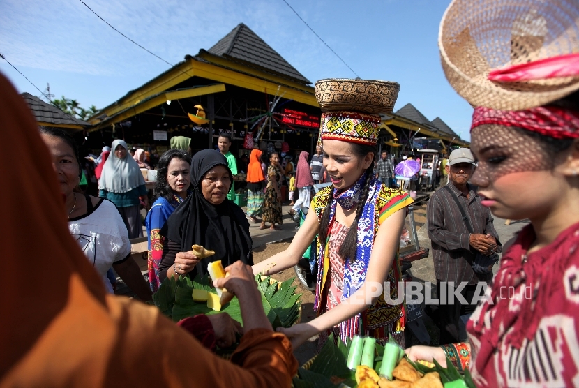 Anggota Komunitas membagikan kue tradisional kepada pengunjung pasar Kenanga saat pembukaan Festival Pasar Rakyat di Pontianak, Kalimantan Barat, Sabtu (22/7). 