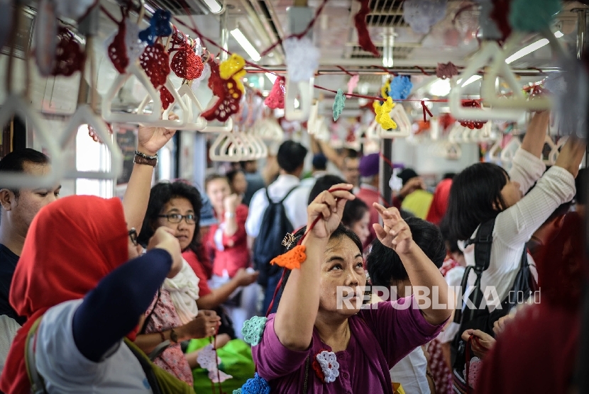 Anggota komunitas Rajut Kejut menghias gerbong Commuter Line tujuan Jakarta Kota dengan kain rajut, Rabu (17/8)
