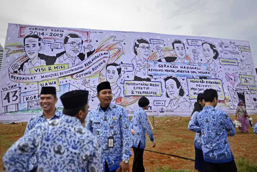 Anggota Korpri berbincang usai upacara di depan baliho berisi slogan pembaruan birokrasi yang dipasang di belakang tenda utama dalam upacara HUT Korps Pegawai Republik Indonesia (Korpri) ke-43 di lapangan Silang Monas, Jakarta, Senin (1/12). 