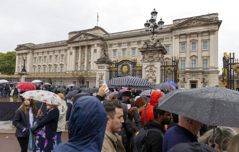 Anggota masyarakat berkumpul di tengah hujan di luar Istana Buckingham, di London, menjelang kedatangan mobil jenazah yang membawa peti mati Ratu Elizabeth II, Selasa, 13 September 2022.