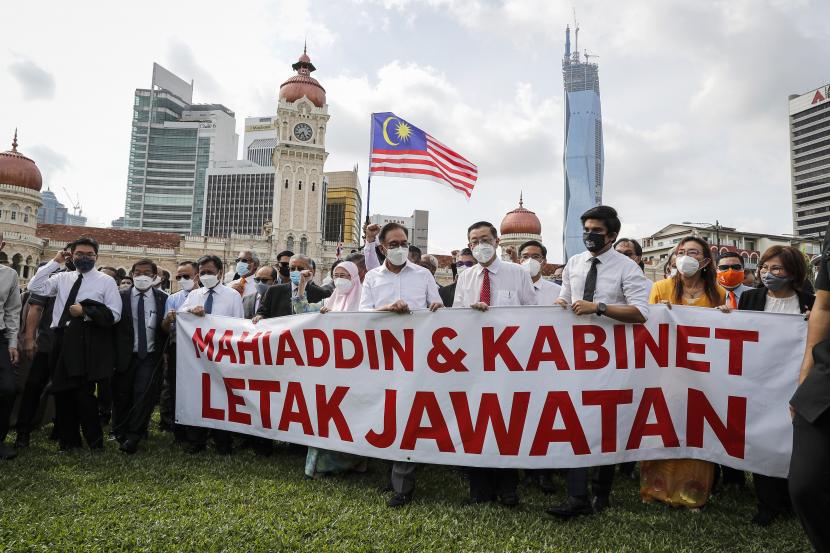 Anggota oposisi Malaysia Anwar Ibrahim, keempat dari kiri, dan Mahathir Mohamad, kedua dari kiri bertopeng biru, memegang spanduk bertuliskan 