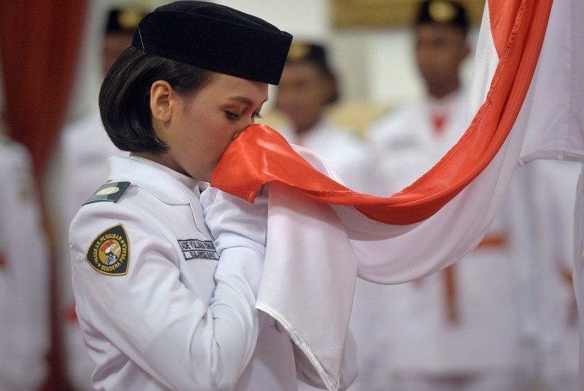 Anggota Pasukan Pengibar Bendera Pusaka (Paskibraka) Nasional 2016 asal Sulawesi Barat Ade Yuliana mencium bendera Merah Putih saat upacara pengukuhan yang dipimpin Presiden Joko Widodo di Istana Negara, Jakarta, Senin (15/8). 