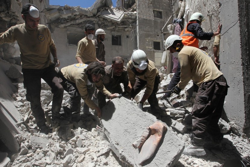Anggota pertahanan sipil mencari para korban selamat setelah terjadinya aksi bombardir di Provinsi Idlib