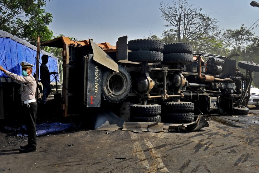 Anggota Polantas mengatur arus kendaraan di dekat truk terguling akibat tabrakan beruntun (ilustrasi)