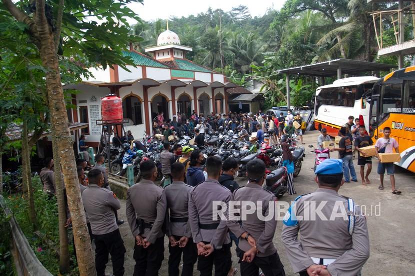 Anggota Polisi berjaga saat warga yang sempat ditahan tiba di halaman masjid Desa Wadas, Bener, Purworejo, Jawa Tengah, Rabu (9/2/2022). Sebanyak 64 warga Desa Wadas dibebaskan oleh pihak kepolisian terkait aksi penolakan pembangunan Bendungan Bener.