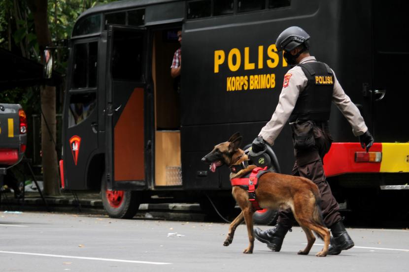 Anggota polisi berjalan dengan anjing pelacak saat mengumpulkan sisa serpihan ledakan bom bunuh diri di depan Gereja Katedral Makassar, Sulawesi Selatan, Senin (29/3/2021). Kepolisian masih melakukan olah TKP serta mengumpulkan serpihan sisa ledakan pada hari kedua pascaledakan bom bunuh diri yang terjadi pada Minggu (28/3/2021) di depan gereja tersebut.