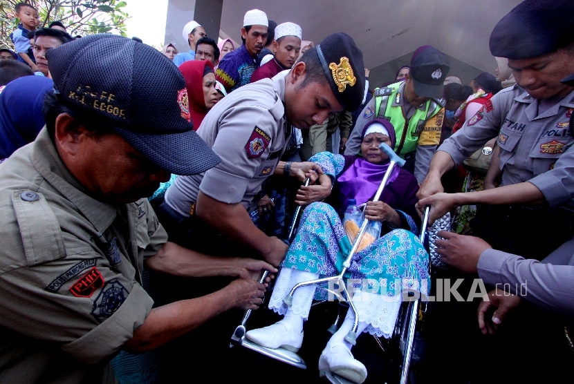 Anggota polisi membantu jemaah calon haji saat pemberangkatan ke embarkasi di kantor Pemda Bogor, Jabar, Selasa (1/8). 