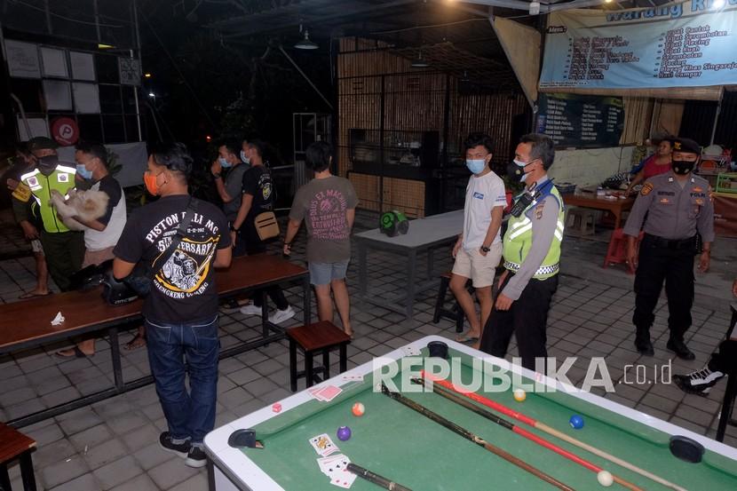 Anggota Polisi membubarkan puluhan warga yang bermain bola sodok dalam Inspeksi Mendadak (Sidak) persiapan Pemberlakuan Pembatasan Kegiatan Masyarakat (PPKM) darurat di Denpasar, Bali, Jumat (2/7/2021) malam. Kegiatan tersebut untuk membina pelaku usaha dan masyarakat mengenai pembatasan aktivitas pada malam hari dalam persiapan penerapan Pemberlakuan Pembatasan Kegiatan Masyarakat (PPKM) darurat yang dimulai pada 3-20 Juli 2021 sebagai upaya mencegah penyebaran varian baru COVID-19.