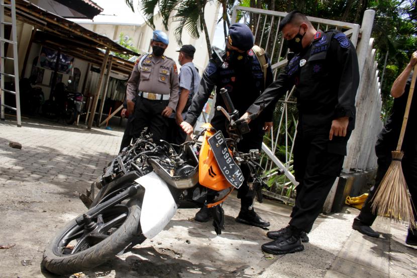 Anggota polisi mengamati motor yang digunakan terduga pelaku bom bunuh diri sebelum dievakuasi di depan Gereja Katedral Makassar, Sulawesi Selatan, Senin (29/3/2021). Kepolisian telah mengidentifikasi salah satu dari dua terduga pelaku bom bunuh diri yang terjadi pada Minggu (28/3/2021) di depan Gereja Katedral Makassa rberjenis kelamin laki-laki berinisial L sedangkan lainnya masih dalam proses identifikasi.