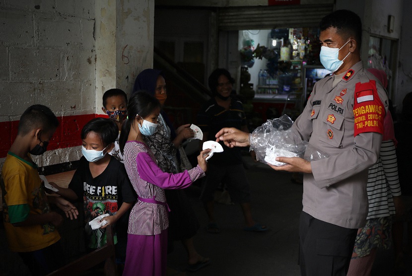 Anggota Polri membagikan masker kepada anak-anak warga Rusun Petamburan, Tanah Abang, Jakarta Pusat, Kamis (22/7). BNPB telah mendistribusikan 30 ribu masker kain dan 30 jerigen handsanitizer ke tiga wilayah di Jakarta untuk mendukung pengetatan PPKM, sebagai upaya dalam memutus rantai penularan COVID-19