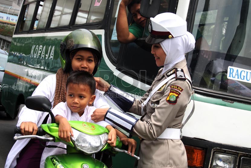   Anggota polwan Bripka Novi dengan mengenakan seragam polisi berjilbab menyapa pengendara motor di lampu merah Bundaran HI, Jakarta Pusat, Senin (25/11).  (Republika/Yasin Habibi)