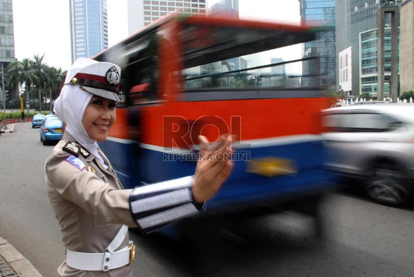  Anggota polwan Bripka Novi mengatur lalu lintas dengan mengenakan seragam polisi berjilbab di lampu merah Bundaran HI, Jakarta Pusat, Senin (25/11).  (Republika/Yasin Habibi)