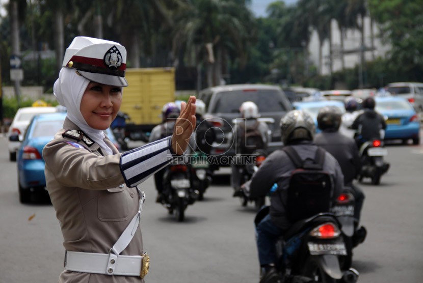  Anggota polwan Bripka Novi mengatur lalu lintas dengan mengenakan seragam polisi berjilbab di lampu merah Bundaran HI, Jakarta Pusat, Senin (25/11).  (Republika/Yasin Habibi)