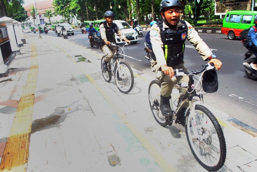 Anggota Satpol PP Kota Bogor melakukan patroli menggunakan sepeda melewati jalur khusus sepeda di pedestrian Kebun Raya Bogor, jalan Juanda, Kota Bogor, Jawa Barat, Jum