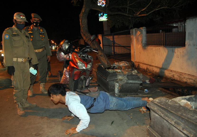 Anggota Satpol PP Kota Bogor memberikan sanksi bagi warga yang tidak menggunakan masker saat patroli jam malam di kawasan Pasar Merdeka, Ciwaringin, Kota Bogor, Jawa Barat.