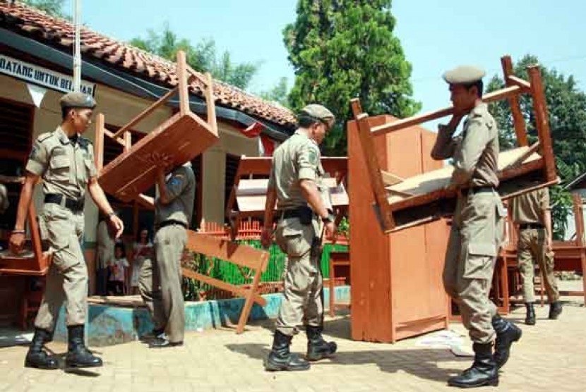  Anggota Satpol PP membereskan meja dan kursi yang dikeluarkan keluarga ahli waris pemilik lahan di SDN Jombang VII, Ciputat, Tangerang Selatan, Kamis (21/6). 