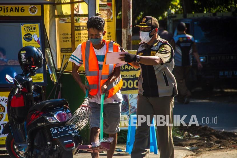 Anggota Satpol PP memberikan sanksi sosial kepada warga yang melanggar protokol kesehatan saat razia yustisi penegakan protokol kesehatan (Prokes) COVID-19 di Banjarmasin, Kalimantan Selatan, Selasa (10/8/2021). Berdasarkan data monitoring kepatuhan protokol kesehatan milik satgas COVID-19 setempat kepatuhan penggunaan masker turun menjadi 86 persen dari semula 94 persen meski kota Banjarmasin resmi memperpanjang PPKM level 4 dari 10 Agustus hingga 23 Agustus 2021. 