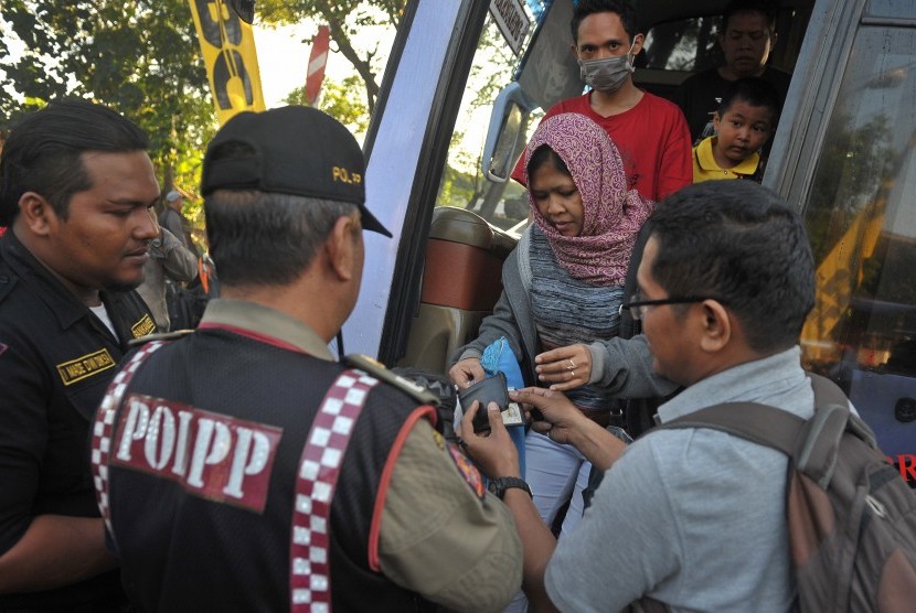 Anggota Satuan Polisi Pamong Praja (Satpol PP) memeriksa kartu identitas penumpang bus saat inspeksi penduduk pendatang pada arus balik H+4 Lebaran di Terminal Ubung, Denpasar, Selasa (21/7). 