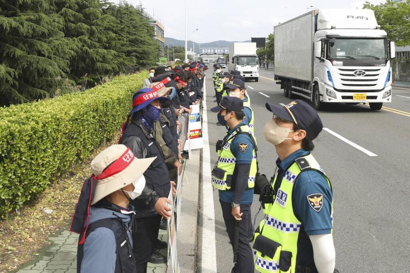 Anggota Solidaritas Pengemudi Truk Kargo memegang spanduk saat petugas polisi berjaga di luar pabrik Hyundai Motor di Ulsan, Korea Selatan, Rabu, 8 Juni 2022.