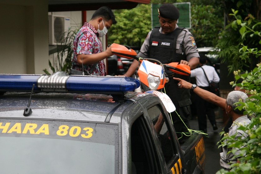 Anggota tim Komisi Pemberantasan Korupsi (KPK) dibantu polisi menaikkan sepeda motor ke atas mobil guna diamankan saat proses penggeledahan oleh KPK di rumah dinas bupati di Nganjuk, Jawa Timur, Senin (5/12).