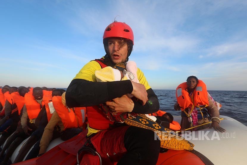 Anggota tim pertolongan dari Spanyol Daniel Calvelo menggendong bayi pengungsi berumur empat hari dalam operasi SAR yang dilakukan LSM Spanyol di Laut Mediterania 22 mil laut utara Kota Sabratha, Libya.